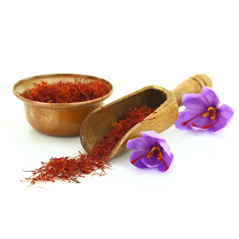 Saffron threads in a brass bowl and scoop with saffron flowers on a white background