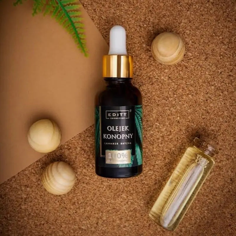 Bottle of Hemp oil 100% face serum Organic and vegan on a cork background with wooden balls and a leaf.