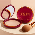 Compact bronzing powder with mirror and a brush on a beige background